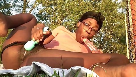 Busty ebony woman is smoking a cigarette in the park